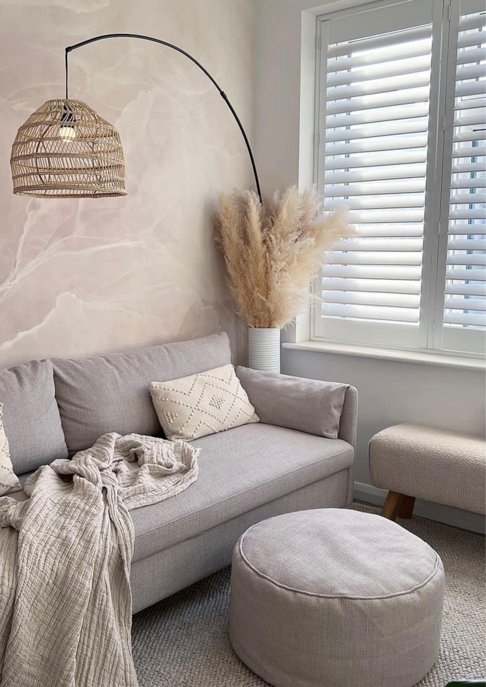 A living room featuring a comfy couch, stylish ottoman, and a bright window letting in natural light.