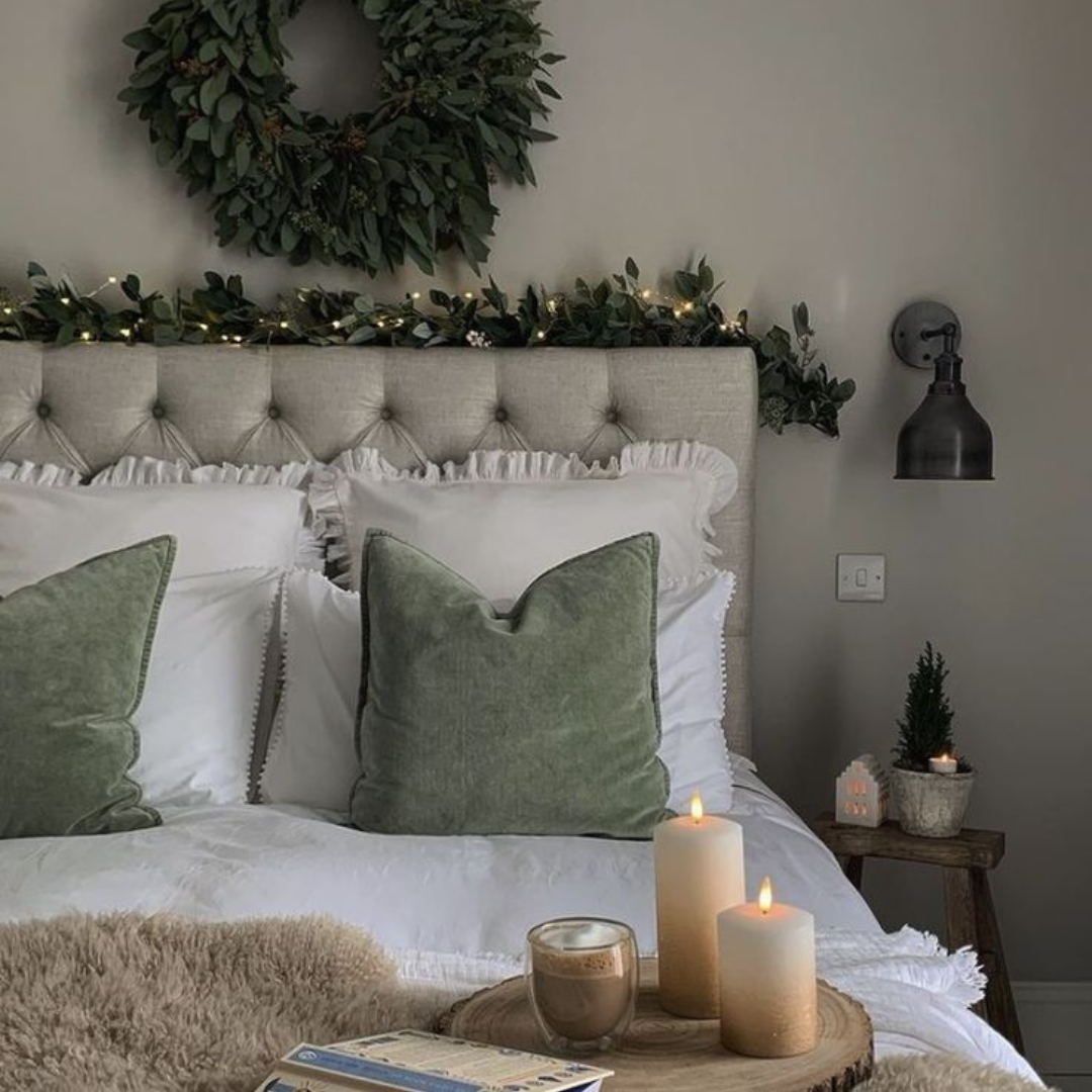 A charming bed decorated with soft candles and a lovely wreath, perfect for a relaxing and peaceful vibe.