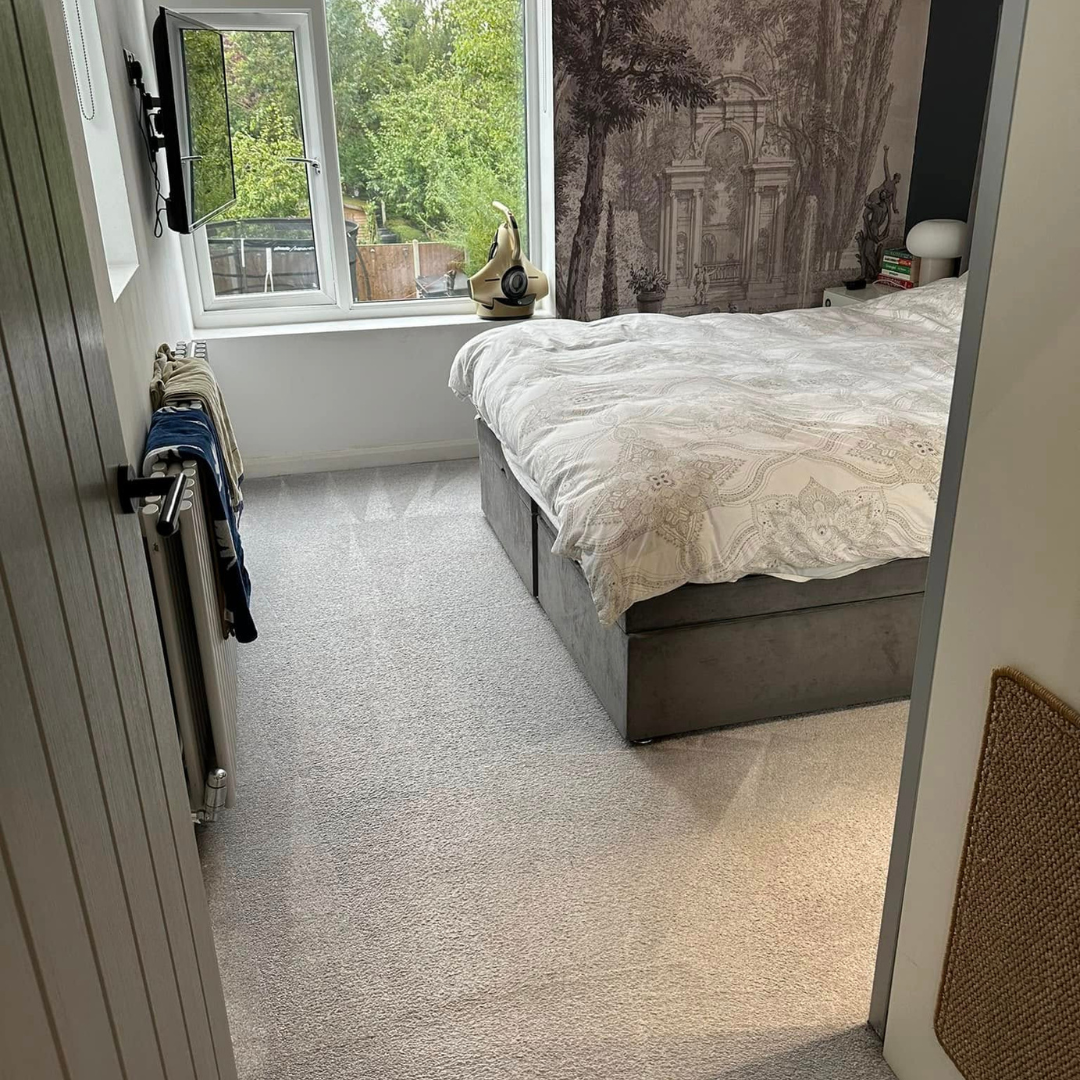 A simple bedroom showcasing a comfortable bed beside a window that offers a view outside.