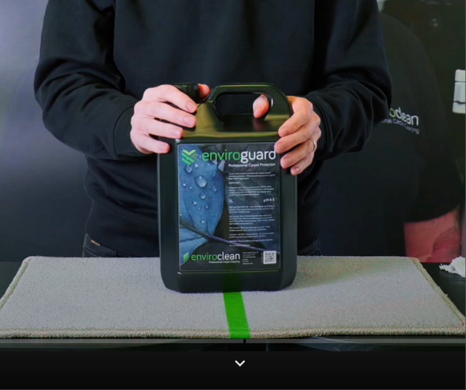 Person holding a black bottle of Enviro Guard cleaning product