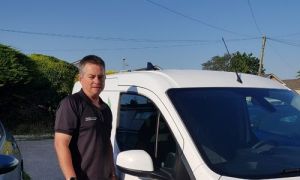 Man standing in front of an "Enviroclean" van with matching uniform on. He appears cheerful, conveying professionalism and enthusiasm.