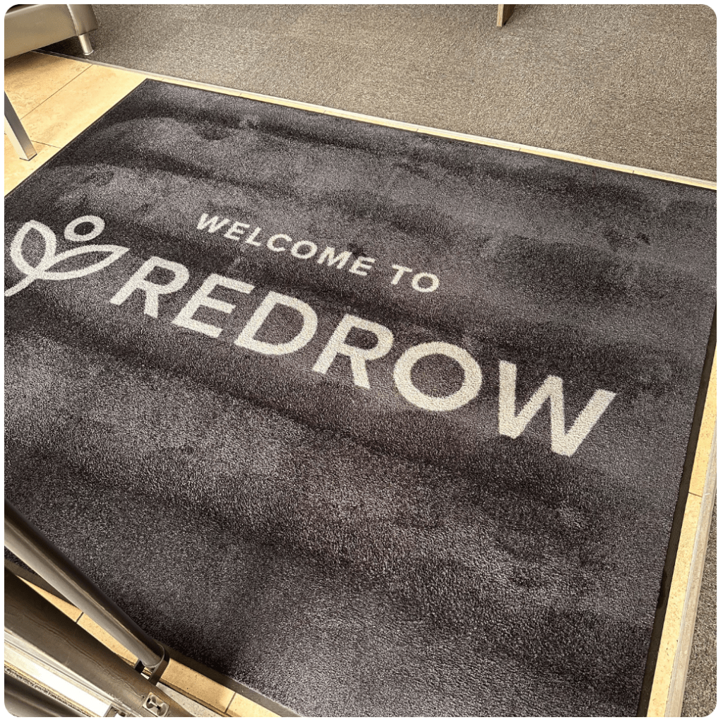 A doormat with the word "Redrow" printed on it, inviting guests to enter.