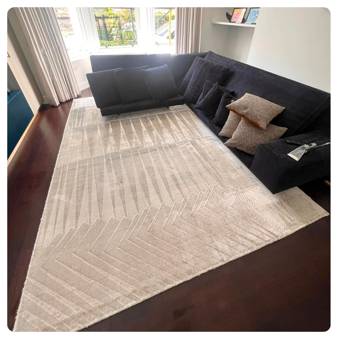 fresh rug in living room with dark sofa, and beige curtains