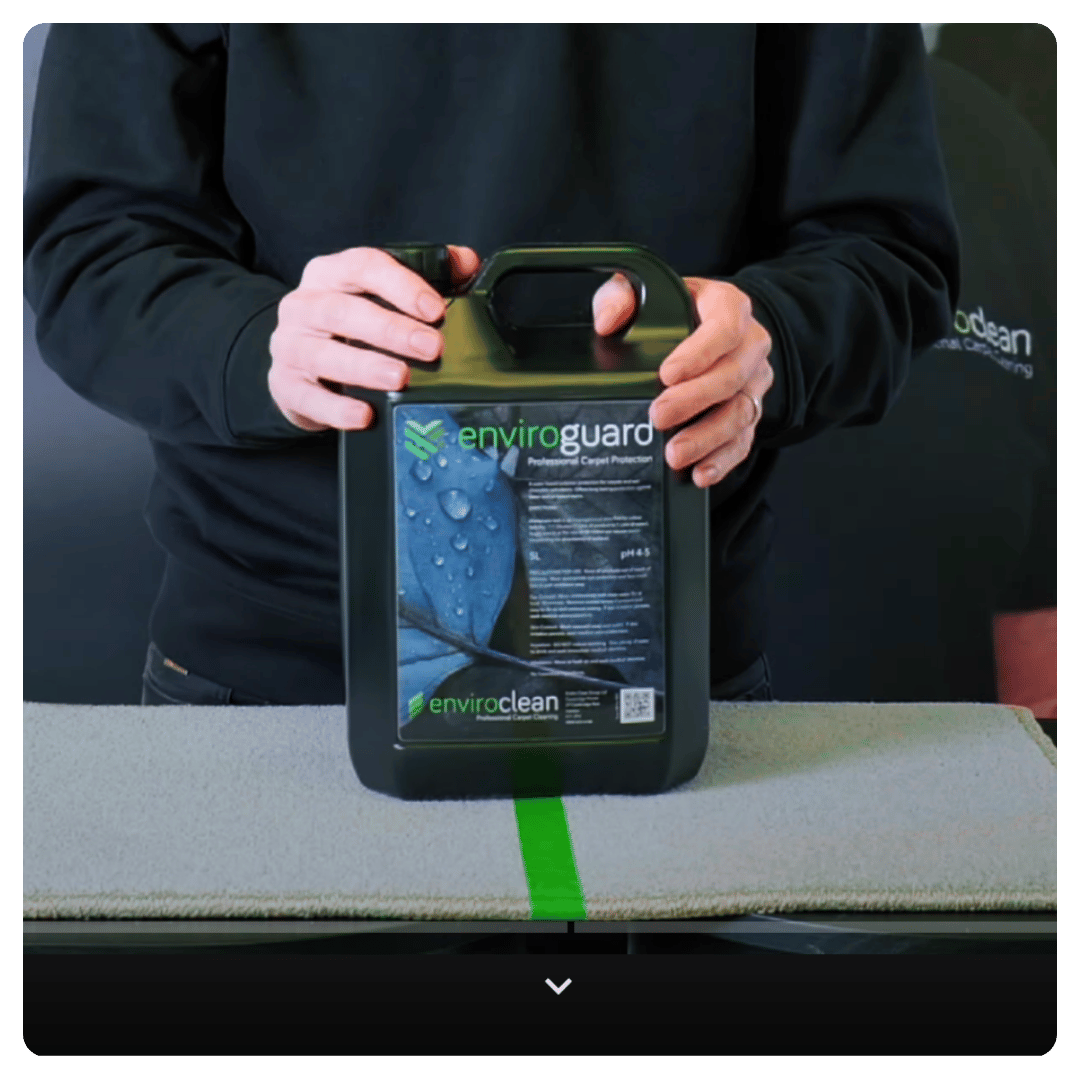 Person in black holds a container labeled "Enviroguard Professional Carpet Protection," professional scene.