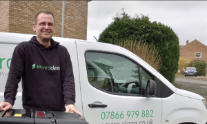 Man infront of branded white enviro clean van with cleaning equipment and uniform, smiling approaching and professional.