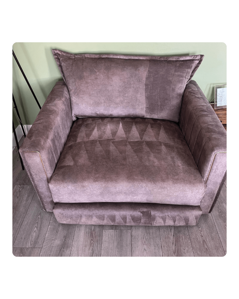 Plush mauve armchair with geometric diamond pattern on seat. It sits on a wooden floor against a light green wall, creating a cozy, modern feel.