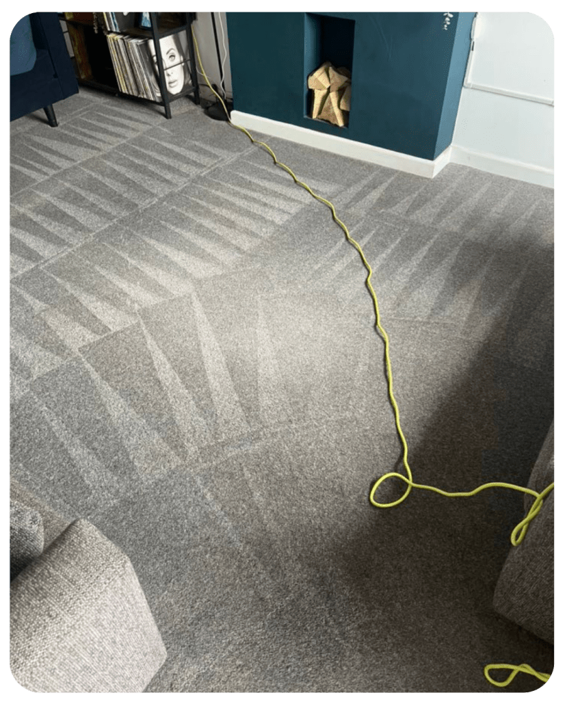 freshly cleaned grey carpet with clean lines in it, and the wire from cleaning equipment still laid across.