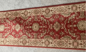 Reg and beige Persian rug silk rug professionally cleaned, laid out on a grey carpet.