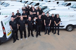Group of enviro clean franchisee's in uniform with their fleet of vans behind them.