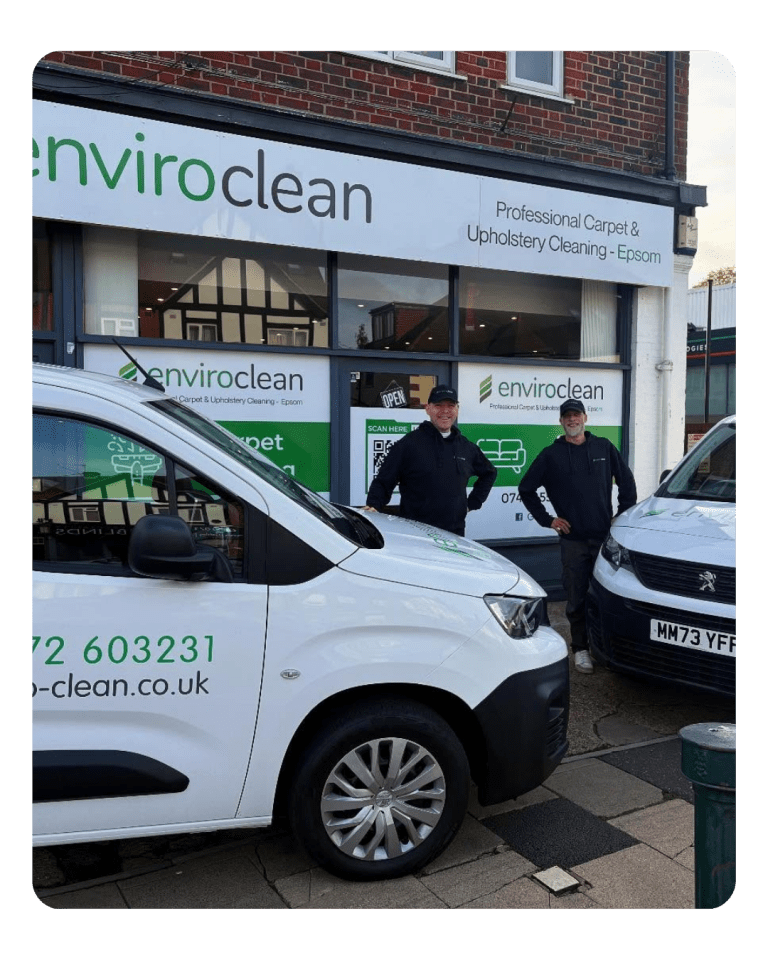 Two smiling men standing in front of their shop, with branded enviro clean vans